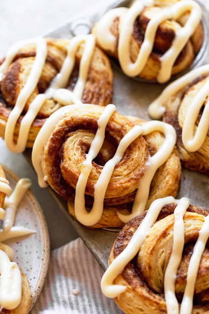 A close up of cinnamon roll biscuits in tin with a design of icin