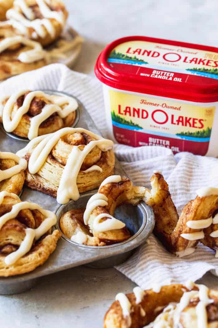 A large baking tin of cinnamon rolls made with biscuit dough with a butter product in the background