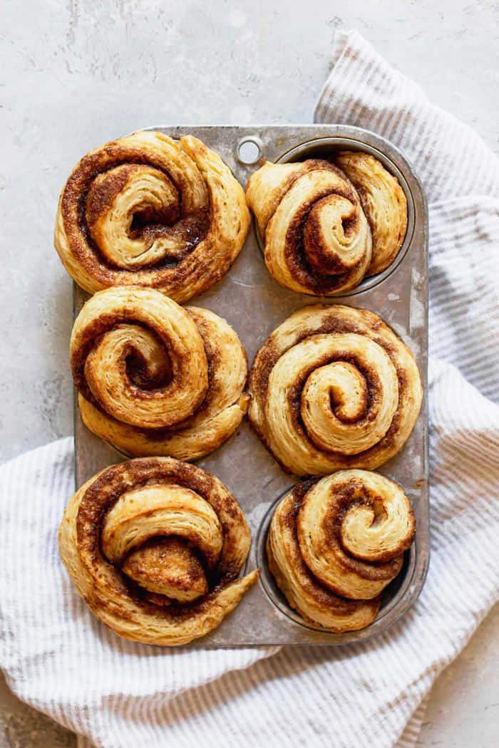 A tin of cinnamon biscuits baked against a gray background and white napkin