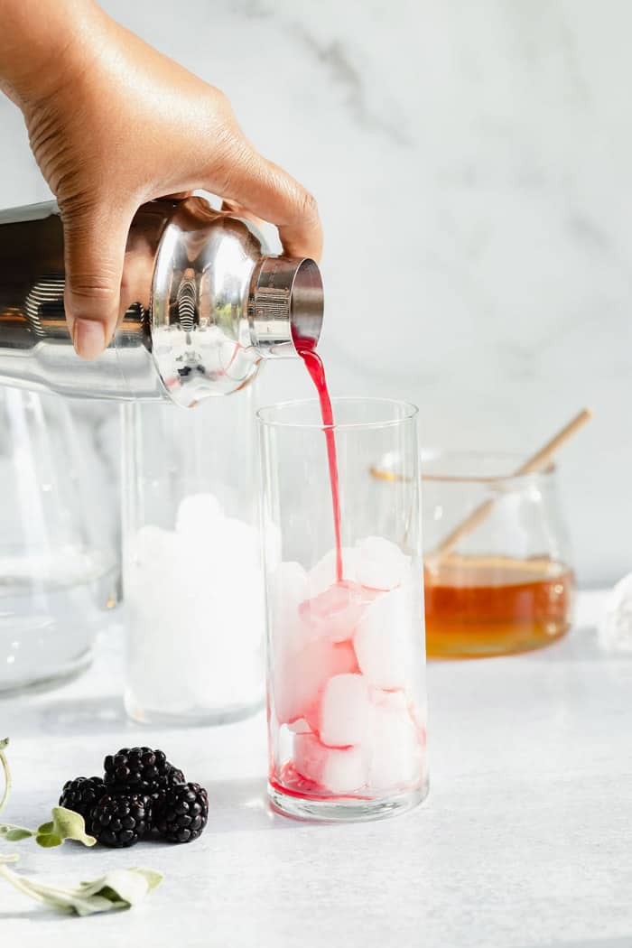 Refresher being poured over ice with honey and blackberries in the background