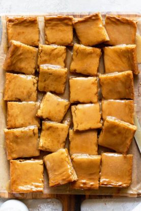 An overhead of 24 maple bars cut and ready to serve on parchment paper