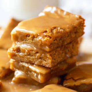 Delicious maple blondies stacked on top of each other with a gooey maple glaze on top