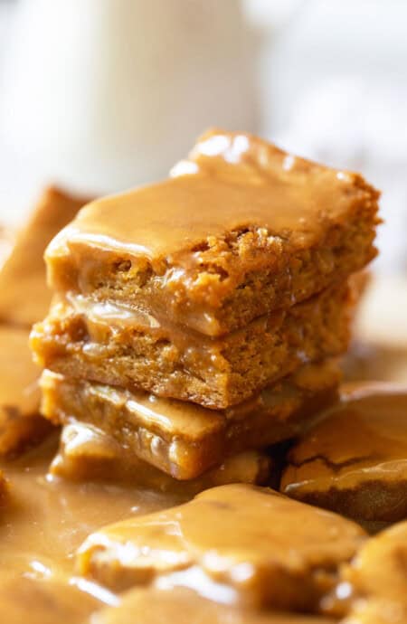 Delicious maple blondies stacked on top of each other with a gooey maple glaze on top