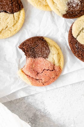 Neapolitan cookies on white parchment paper with a bite out of one