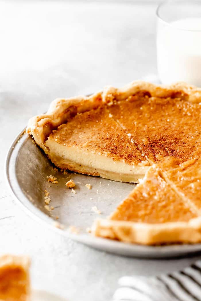 An egg custard pie recipe with slices missing on white countertop