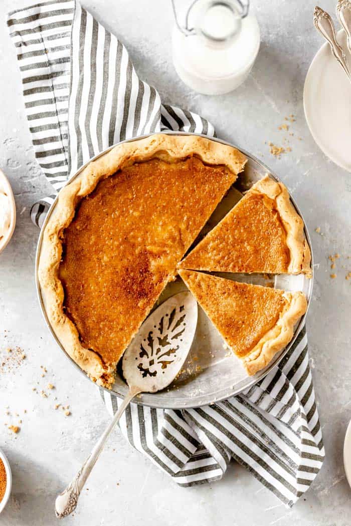 A whole pie with slices missing against a striped napkin against a white background