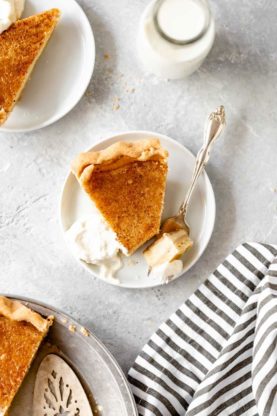 Slices of egg pie on white plates with one being eaten with a fork and whipped cream