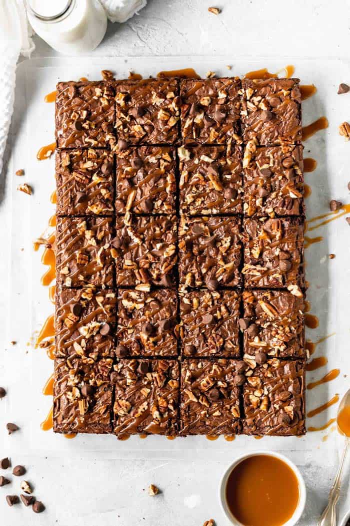 Brownies cut and ready to serve pieces from with a bowl of caramel next to it