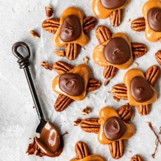 An overhead of several turtle candies with a spoon dipped in chocolate