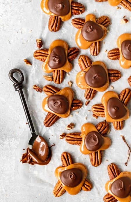 An overhead of several turtle candies with a spoon dipped in chocolate