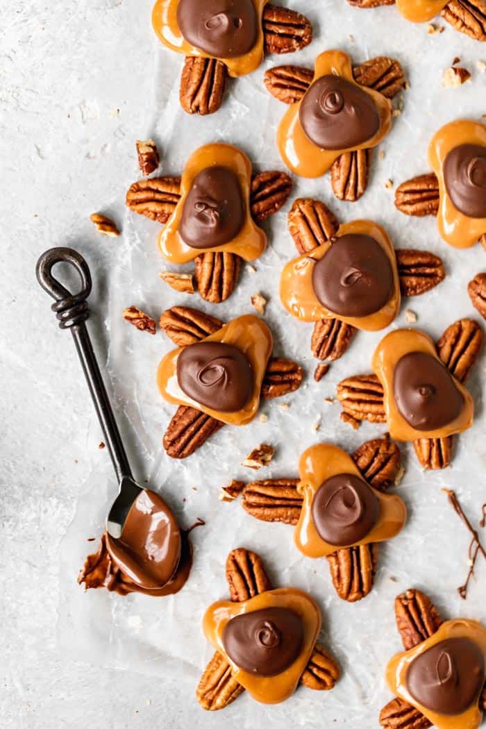 An overhead of several turtle candies with a spoon dipped in chocolate