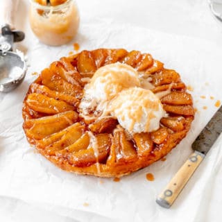 A classic french apple tarte ready to serve with ice cream and cream sauce against white background