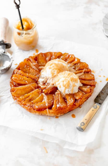 A classic french apple tarte ready to serve with ice cream and cream sauce against white background