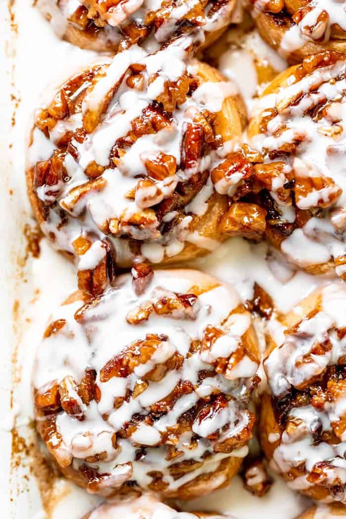 Pecan cinnamon rolls after being drizzled with a cream cheese icing in baking dish