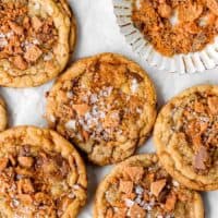 Brown butter cookies with sprinkled salt on top scattered against on a white background