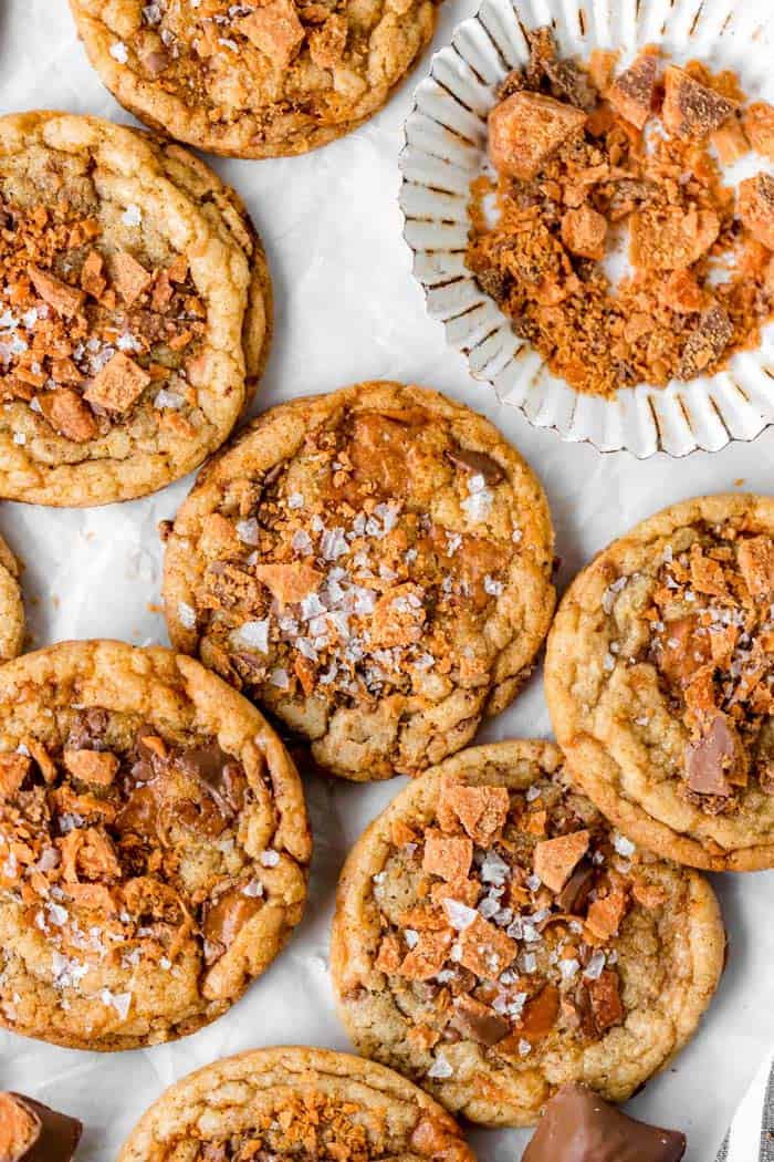 Brown butter cookies with sprinkled salt on top scattered against on a white background