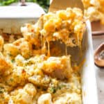 Cauliflower mac and cheese being lifted from pan to serve