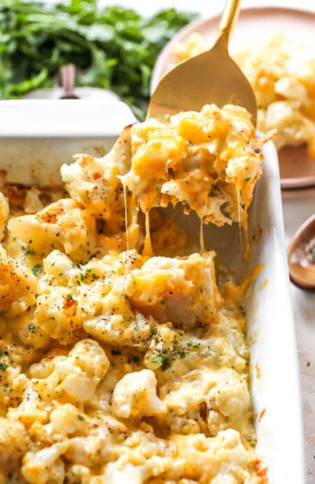 Cauliflower mac and cheese being lifted from pan to serve