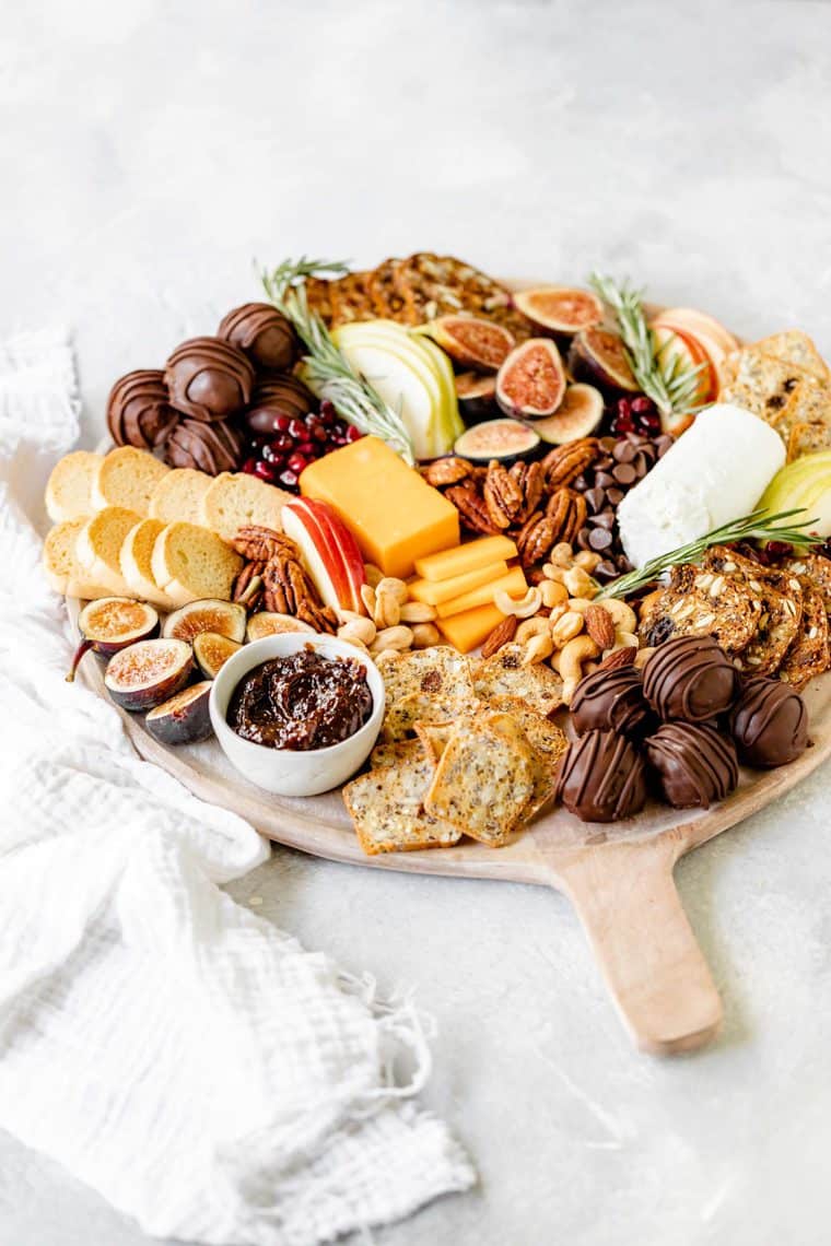 A full charcuterie board filled with cheeses, chocolate, figs and other fruit ready to serve