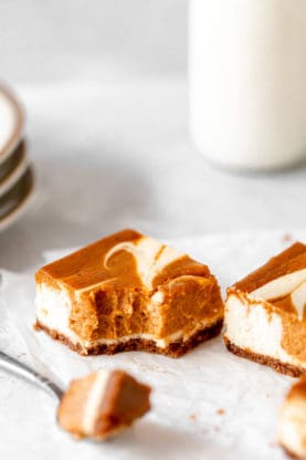 A close up of eaten pumpkin swirl cheesecake bar with a fork ready to eat