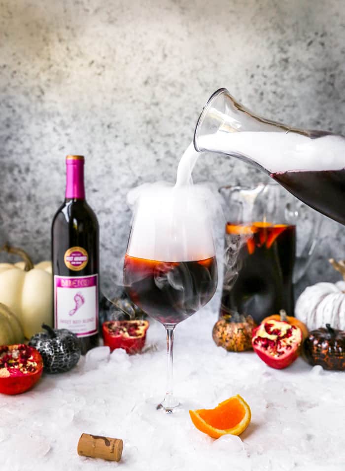 Sangria being poured into a wine glass with dry ice