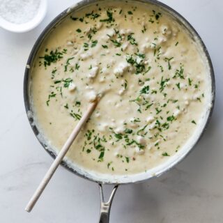 An overhead shot of pan filled with sawmill gravy with a wooden spoon ready to serve