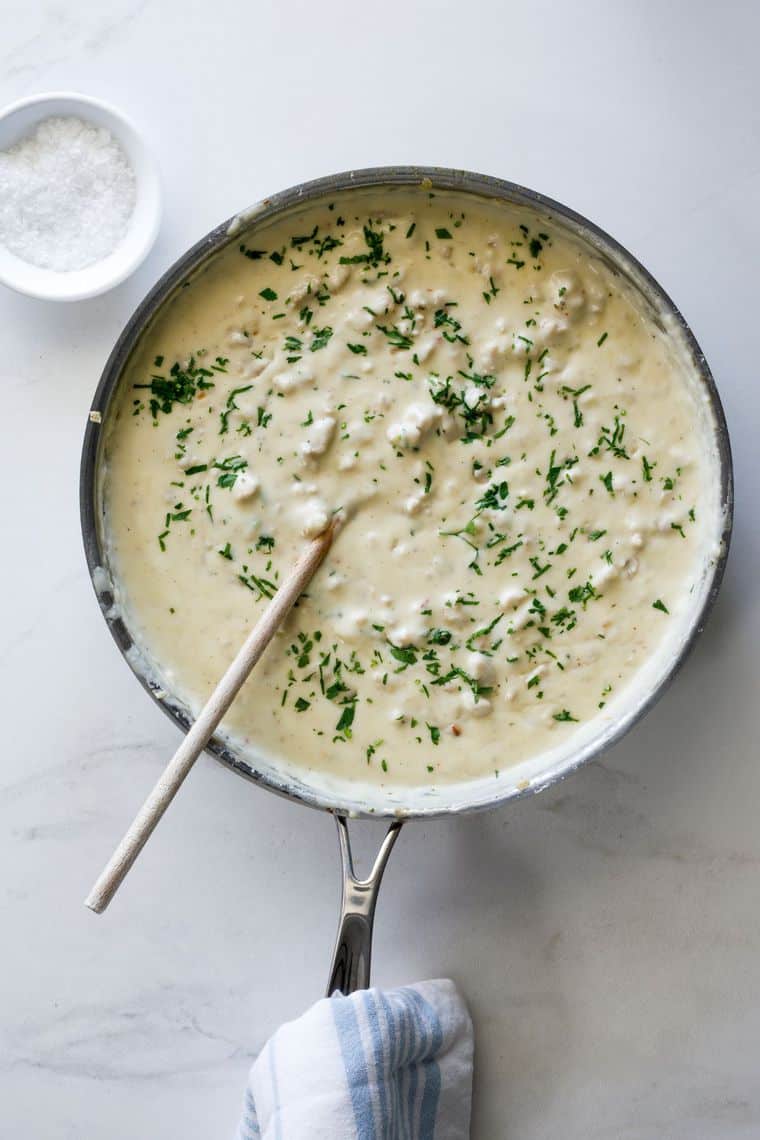 An overhead shot of pan filled with sawmill gravy with a wooden spoon ready to serve