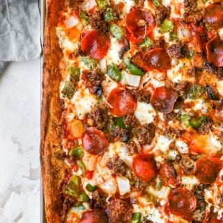 An overhead of a full sheet of deep dish pizza with pepperoni and sausage and peppers