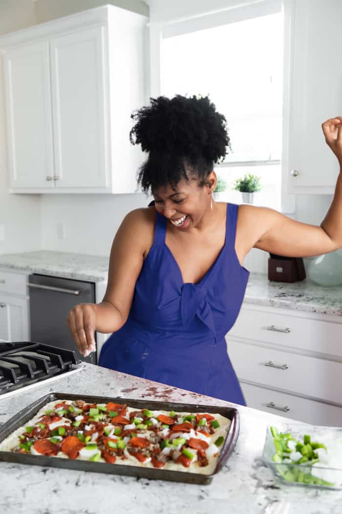 Jocelyn Delk Adams in the kitchen dancing while making pizza