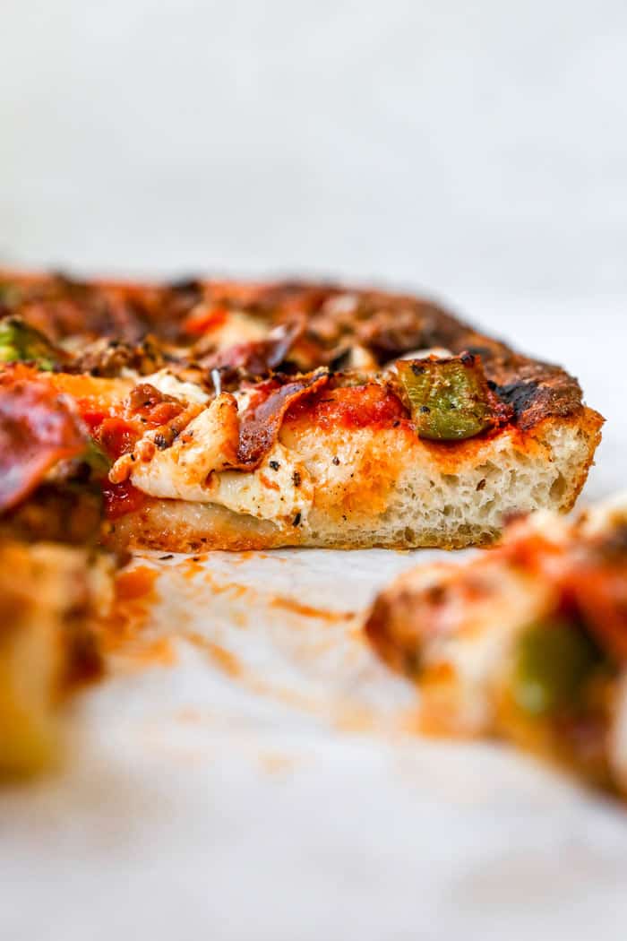 A close up of sliced sicilian pizza with thick crust and cheese melted on top