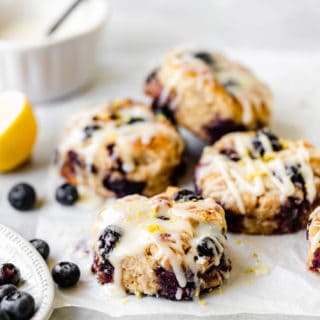 A stack of blueberry lemon drop biscuits piled high with scattered blueberries and lemon slices nearby