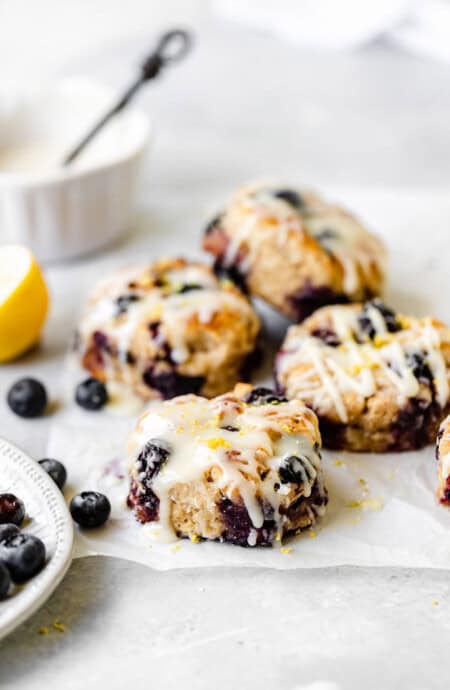 A stack of blueberry lemon drop biscuits piled high with scattered blueberries and lemon slices nearby