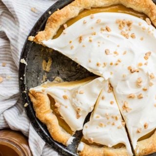 An overhead of caramel pie with one slice missing and two slices ready to serve