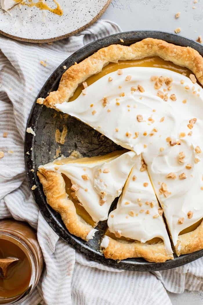 An overhead of caramel pie with one slice missing and two slices ready to serve