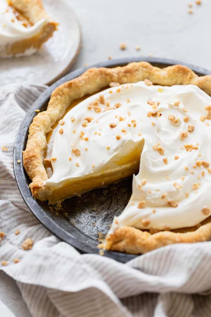 A close up of sliced pie filled with caramel for Thanksgiving against striped napkin