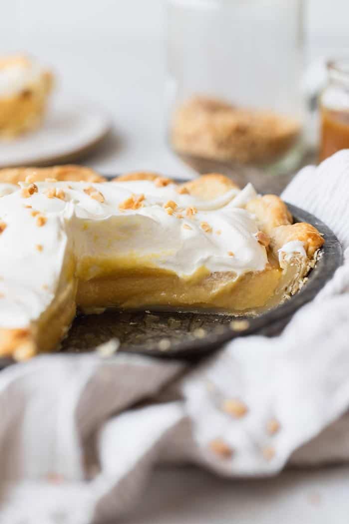 A close up of sliced caramel filled pie topped with whipped cream and butterscotch chips