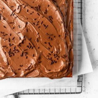 The corner of a sheet cake topped with chocolate swiss meringue buttercream and chocolate sprinkles