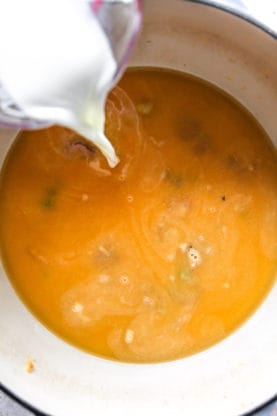 Whole milk being poured into a stew stock base