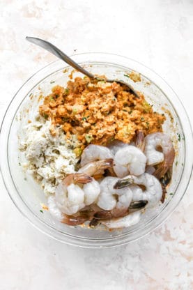 A mix of fresh seafood in a bowl with cornbread crumbs, seasoning, spices and more to make a stuffing