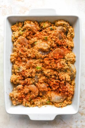 seafood cornbread dressing with spice on top in a white baking pan