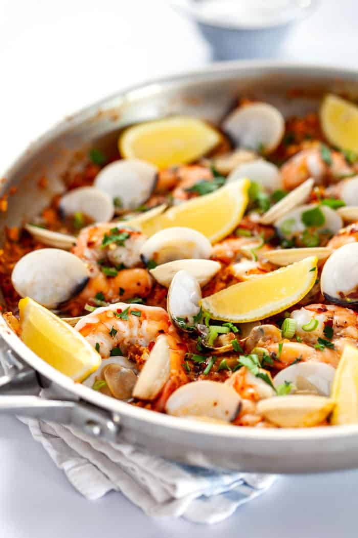 A silver skillet filled with a completed paella filled with shrimp and clams ready to serve