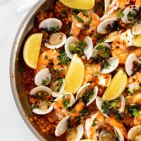 A close up of a completed skillet of seafood paella filled with mussels, shrimp and clams ready to serve