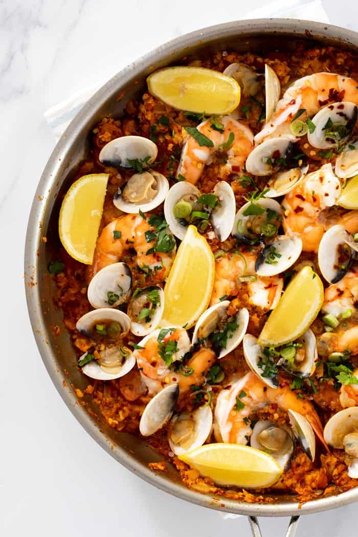 A close up of a completed skillet of seafood paella filled with mussels, shrimp and clams ready to serve