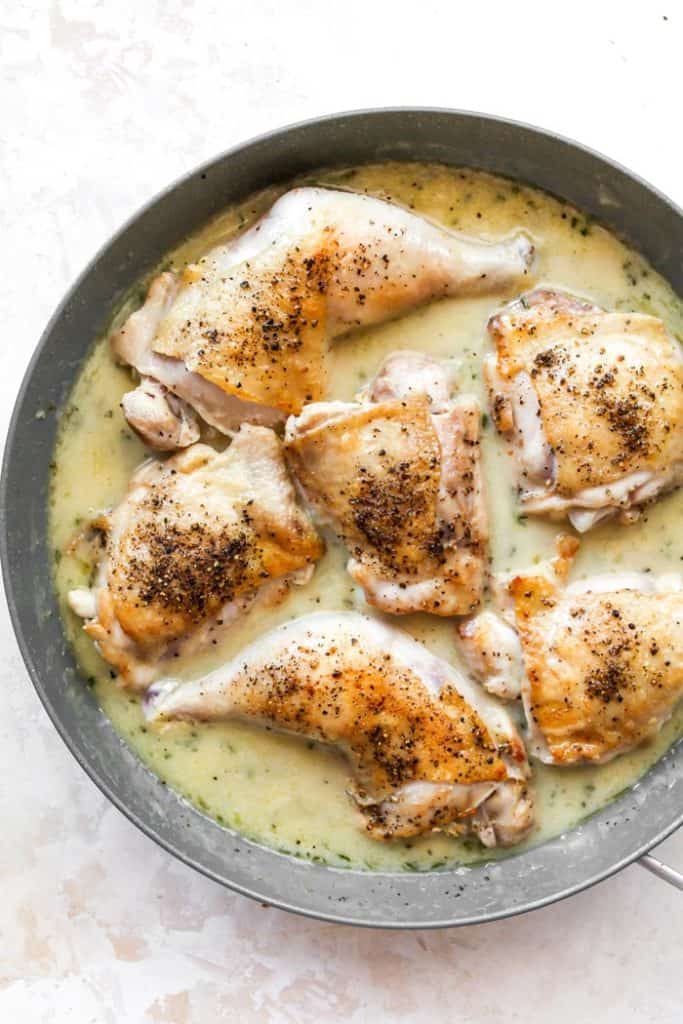 Chicken quarters cooking in a white wine sauce reducing to thicken
