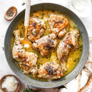 Chicken in a wine garlic sauce with a spoon serving the sauce