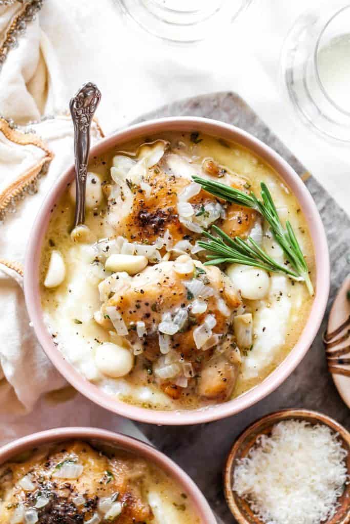 Two bowls of braised chicken in white wine sauce over creamy grits