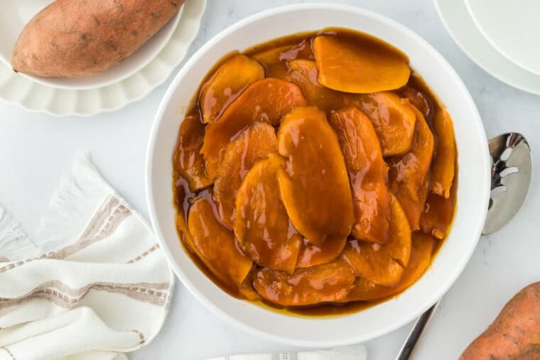 Sliced old fashioned candied sweet potatoes in a white bowl on white countertop ready to serve