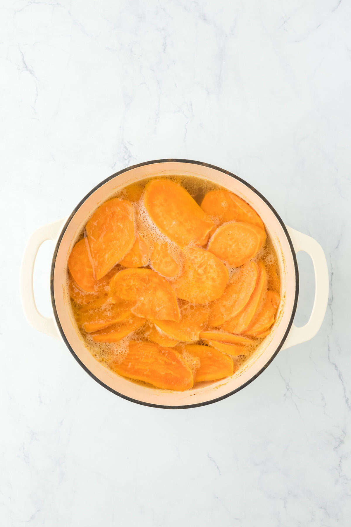 Boiling sliced sweet potatoes in a white pot