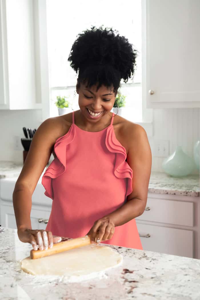 Jocelyn Delk Adams rolling out pie dough to add to a pie plate