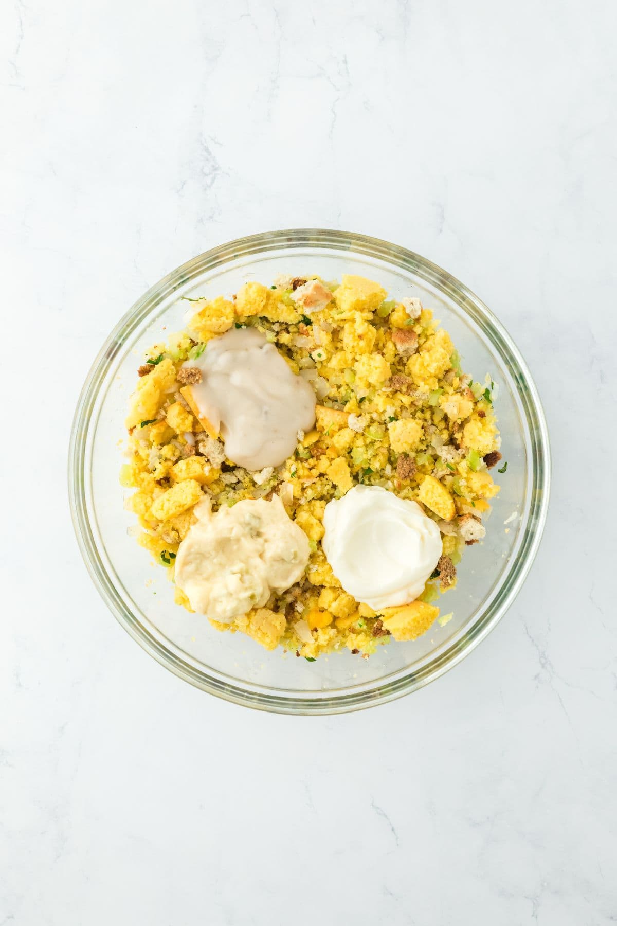 A bowl showing cornbread mixture with added mayo, cream of mushroom and celery and seasonings